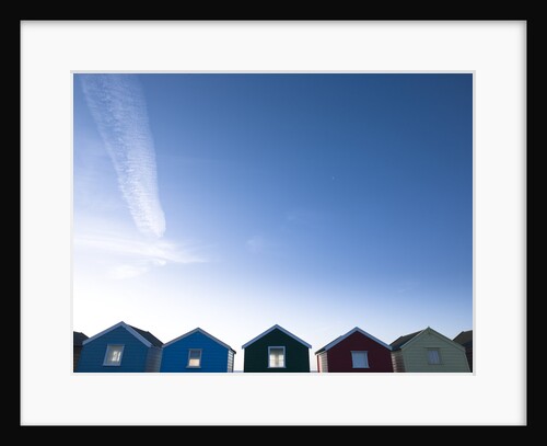 Beach huts in a row against blue skies by Assaf Frank